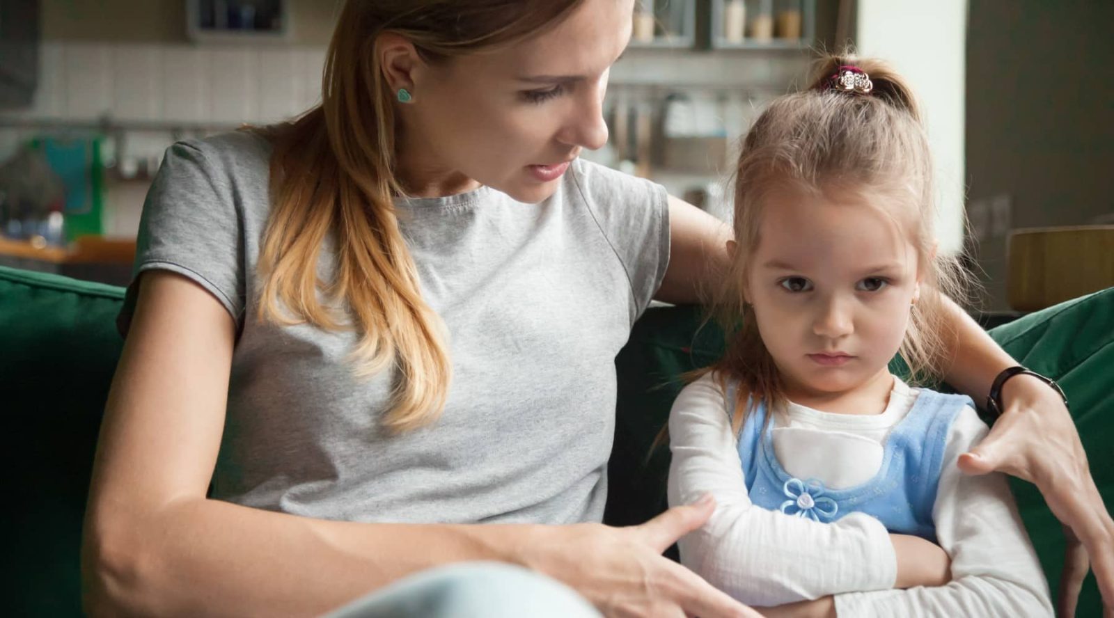 Mother talking to resistant daughter on sofa, illustrating parental alienation