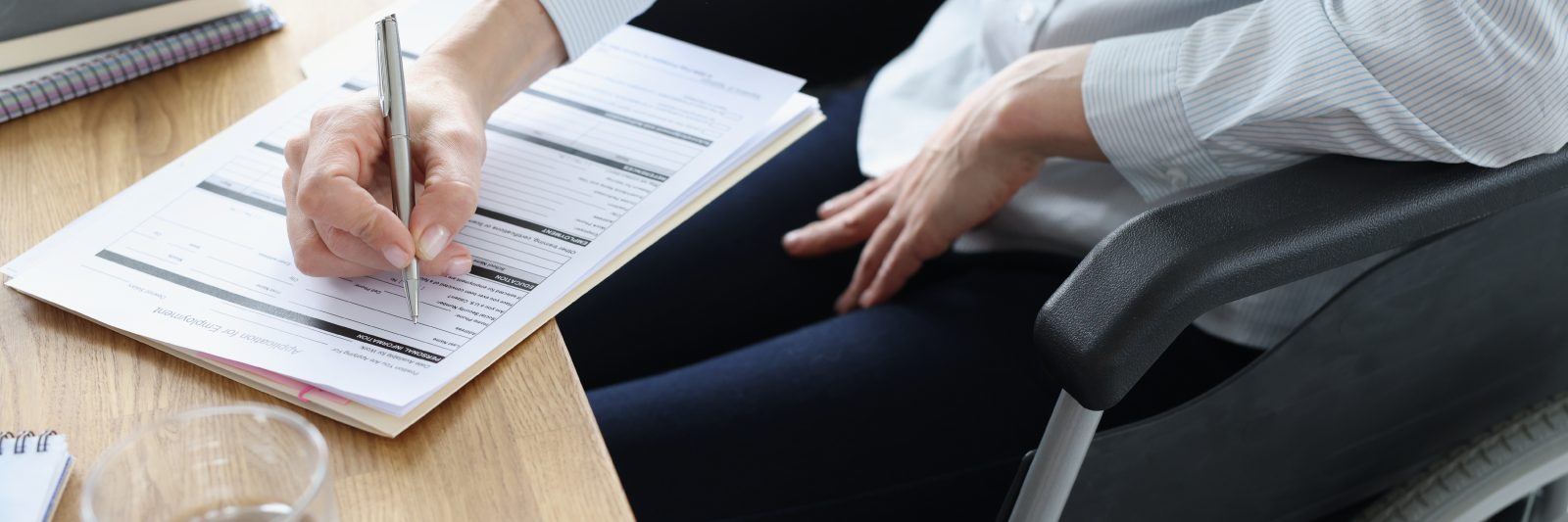 A person filling out a job application form with a pen.
