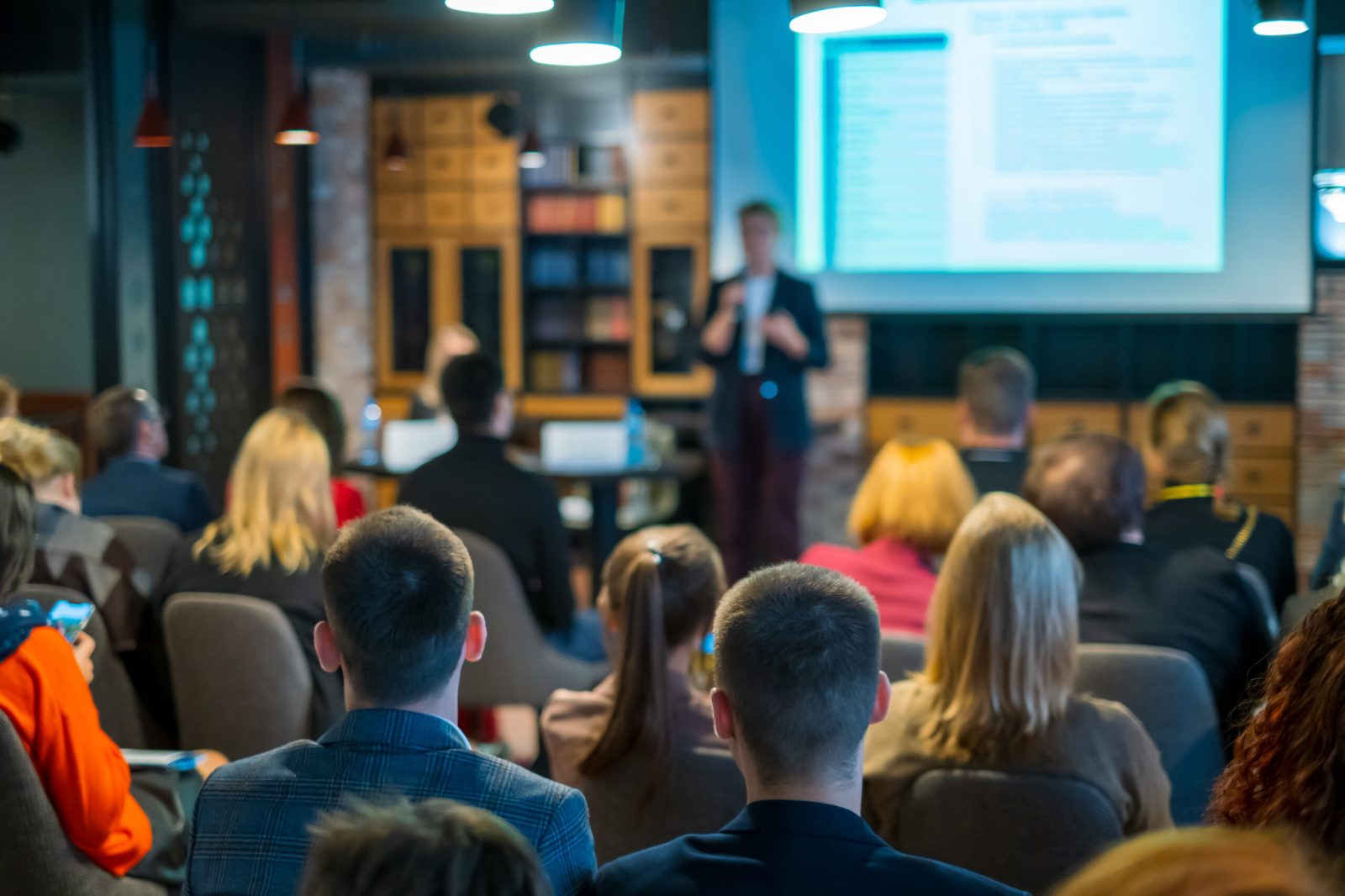 A workplace training session with a presenter addressing a group of professionals in a conference room.
