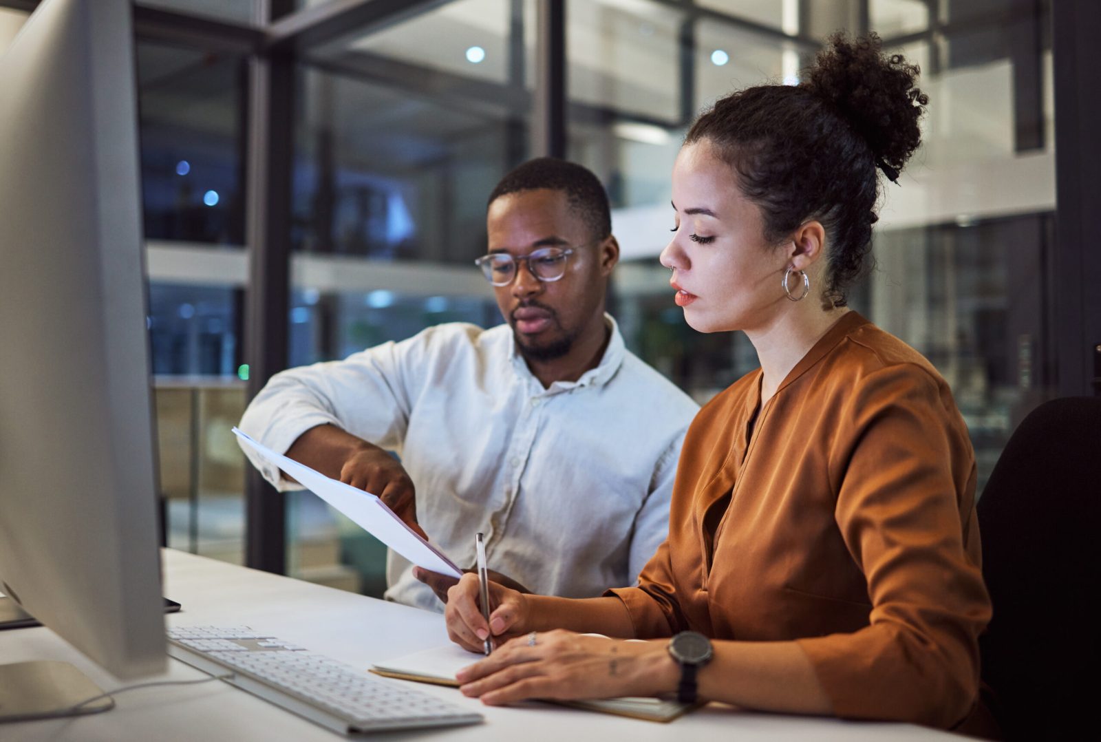 Two professionals discussing and reviewing legal documents at a desk.