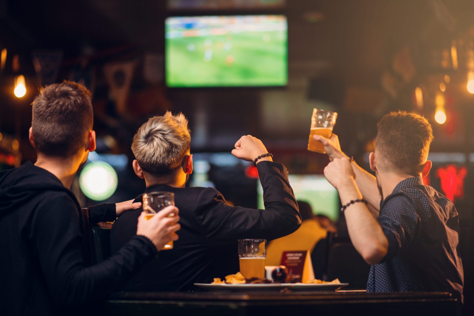 Friends watching England’s World Cup 2026 match on TV in a pub
