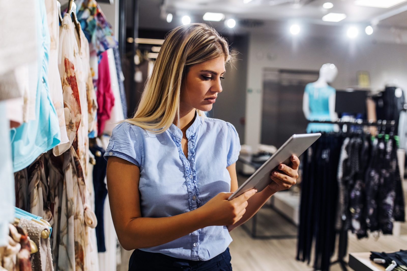 Blonde employee using an iPad in a clothing store