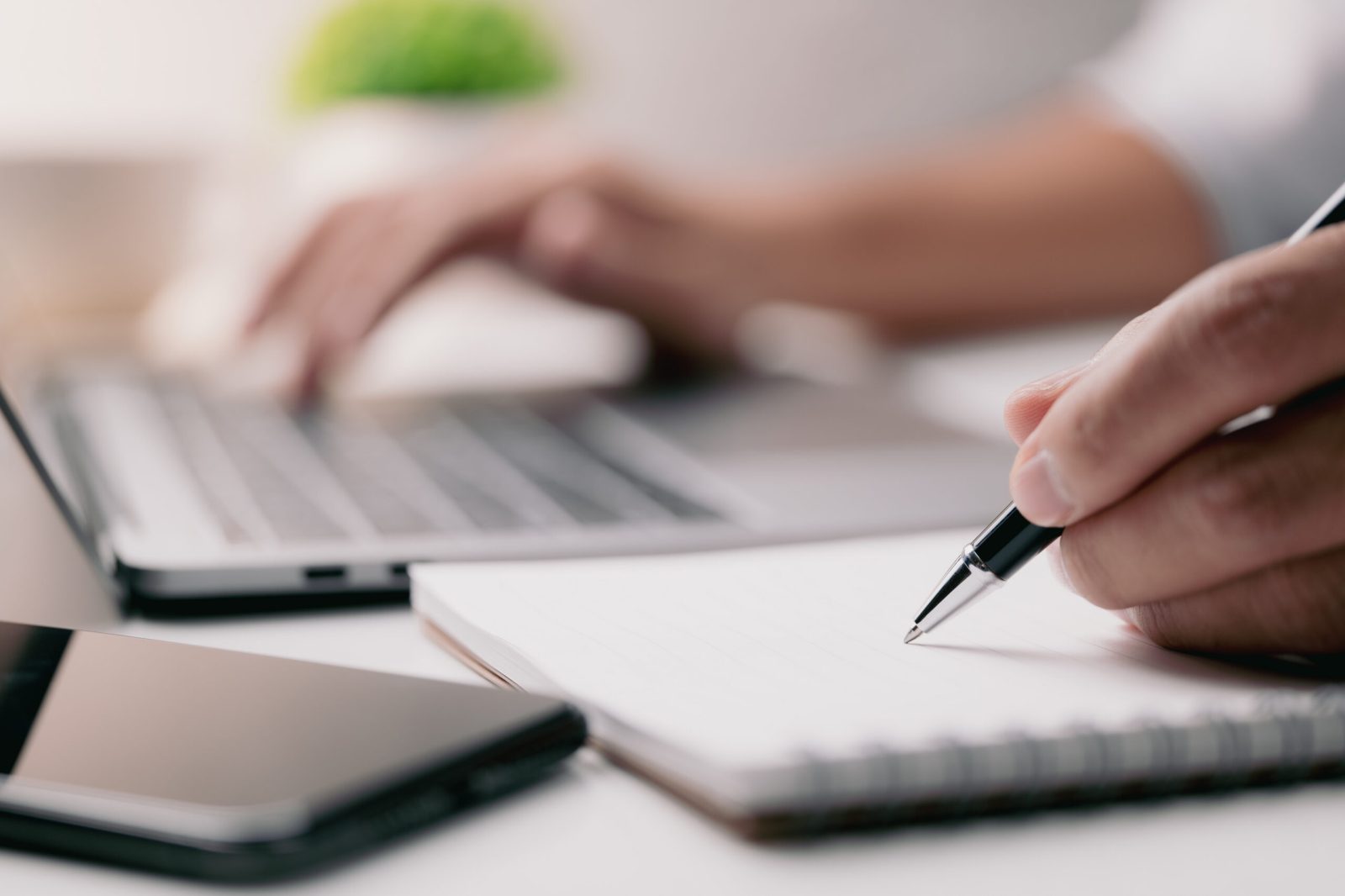 Hand reviewing and marking a contract beside a laptop, representing legal review of supplier agreements and AI-related contractual risks.