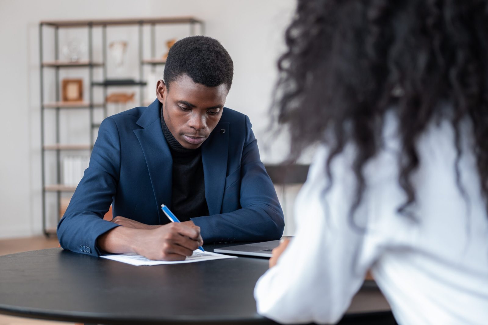 Employee signing a document in a modern office meeting room, with colleague present.