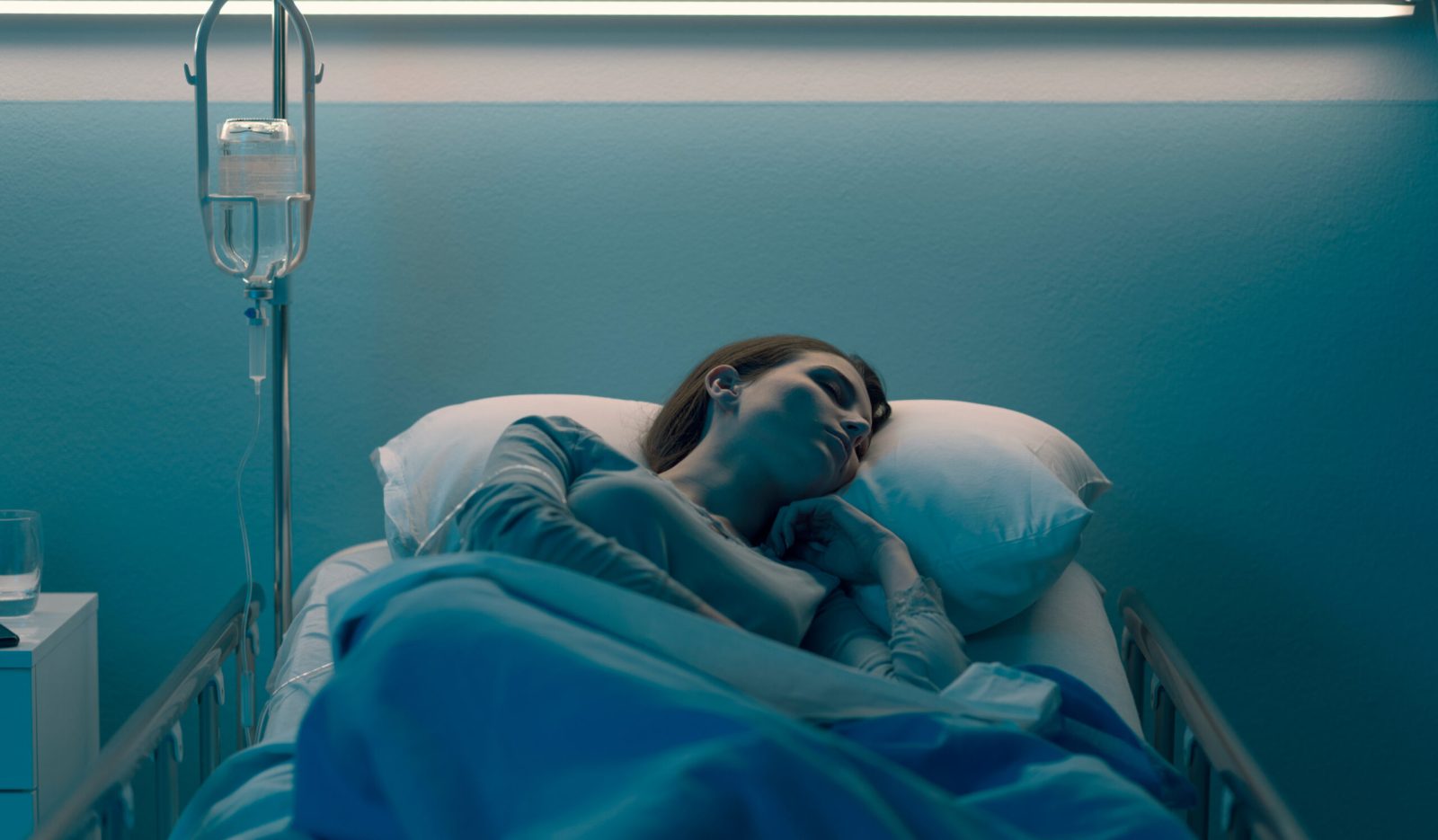 Woman resting in a hospital bed, representing the impact of a long-term health condition affecting work.