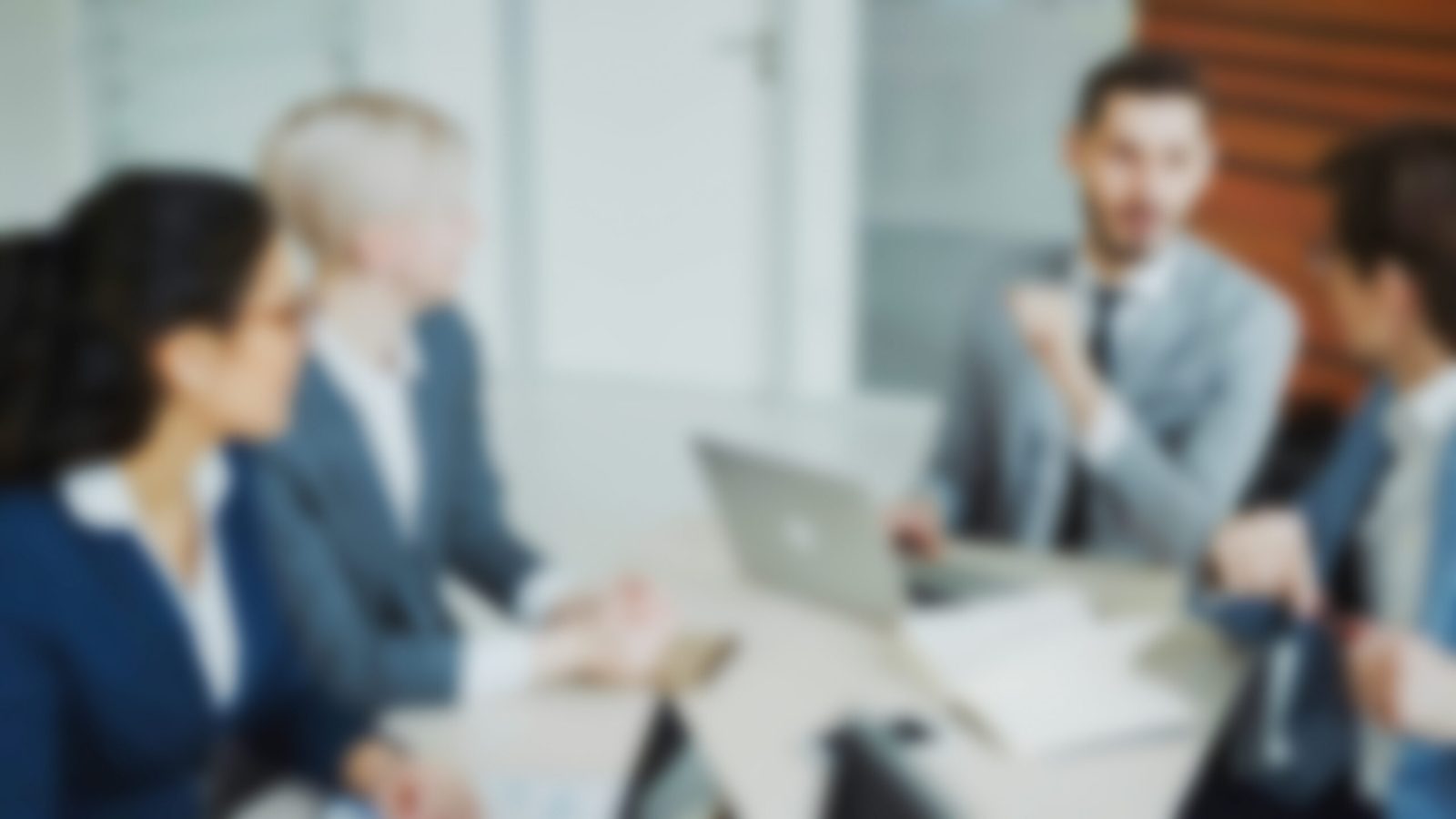 Blurred image of business professionals seated around a boardroom table during a corporate meeting